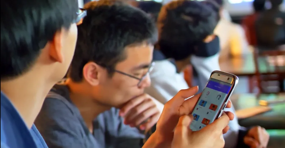 Fans at a table, one answering a live Taunt question on a phone.